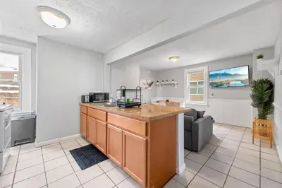 a kitchen with a counter and a living room at Little Italy Group Stay 4 TV's Pet Friendly in Cleveland