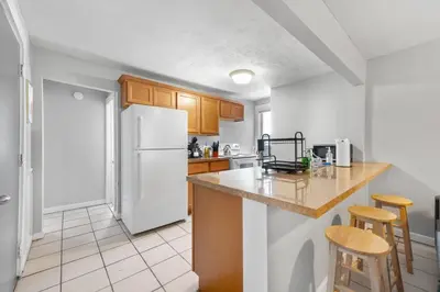 a kitchen with a white refrigerator and wooden cabinets at Little Italy Group Stay 4 TV's Pet Friendly in Cleveland