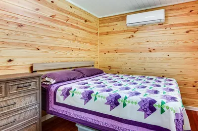 a bedroom with a bed and a wooden wall at Cottage Close to Caves and Trails in Hocking Hills! in Logan