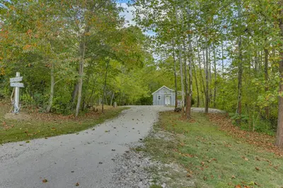 a road leading to a blue house in the woods at Cottage Close to Caves and Trails in Hocking Hills! in Logan