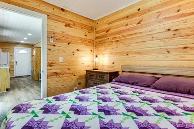 a bedroom with a bed and a wooden wall at Cottage Close to Caves and Trails in Hocking Hills! in Logan