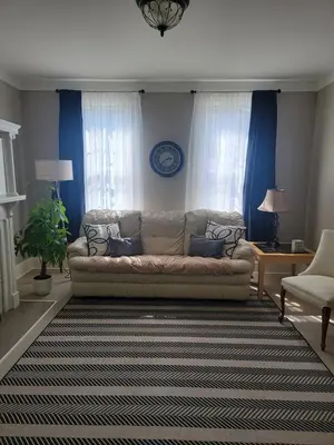 a living room with a couch and blue curtains at 1895 meets 2025 Townhouse in Hamilton
