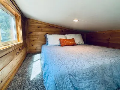 a bedroom with a bed in a wooden cabin at Creekside Haven Tiny Home