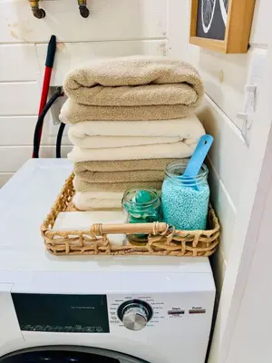 a basket on top of a washing machine with towels at Creekside Haven Tiny Home