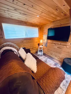 a large couch in a room with a flat screen tv at Creekside Haven Tiny Home