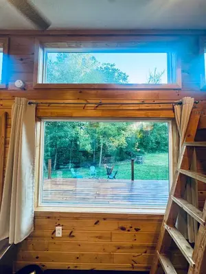 a window in a tiny house looking out at a deck at Creekside Haven Tiny Home