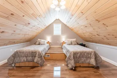 two beds in a attic room with wooden ceilings at White Fern