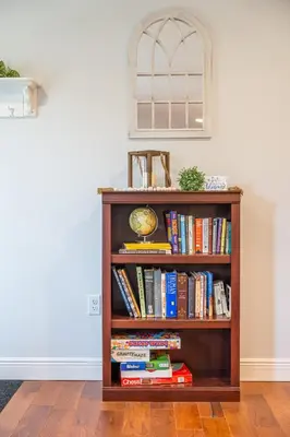 a book shelf with books and a clock on it at White Fern