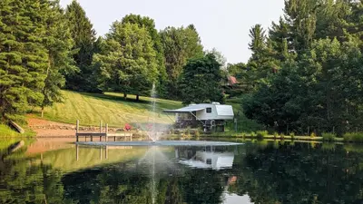 a boat in the middle of a lake with a fountain at Whispering Pines Retreat (RV) in Glenmont