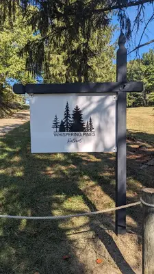 a sign for a park with trees on it at Whispering Pines Retreat (RV) in Glenmont