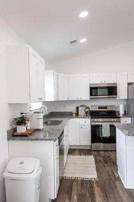 a white kitchen with white cabinets and a toilet at Creek View Cottage