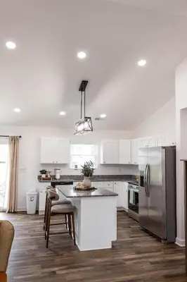 a kitchen with white cabinets and a kitchen island with chairs at Creek View Cottage