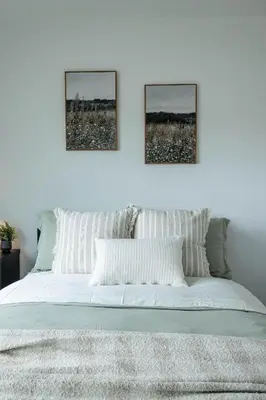 a white bed with two pictures on the wall at Creek View Cottage
