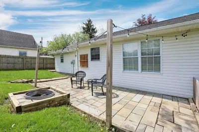 a backyard with two chairs and a fire pit next to a house at Quiet Ranch Retreat for Work Crews & Families Johnstown OH