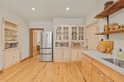 a kitchen with a stainless steel refrigerator and wooden cabinets at Spacious Historic 8-Bedroom Manor in Short North - Perfect for Large Groups in Columbus