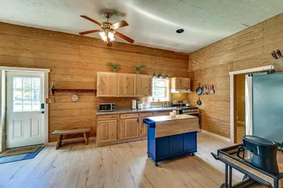 a kitchen with wooden walls and a ceiling fan at Ohio Hunters Cabin with Pond Access Pets Welcome!