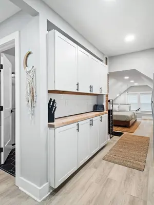 a kitchen with white cabinets and a living room at Unique BOHO Ohio City Loft Apt in Cleveland