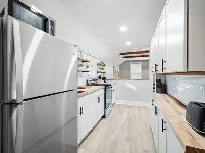 a kitchen with white cabinets and a refrigerator at Unique BOHO Ohio City Loft Apt in Cleveland