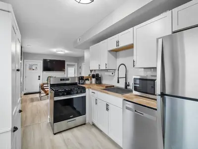 a kitchen with white cabinets and stainless steel appliances at Amazing Boho Oasis Apartment in Ohio City in Cleveland