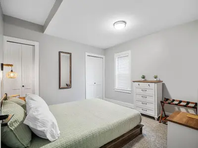 a white bedroom with a bed and a dresser at Amazing Boho Oasis Apartment in Ohio City in Cleveland