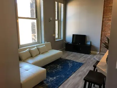 a living room with a white couch and a tv at Renovated Downtown Condo in the HEART OF IT ALL in Cleveland