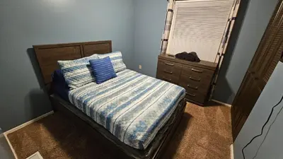 a bedroom with a bed with a blue comforter and a window at 3 BDR - Your Perfect Getaway! in Warren