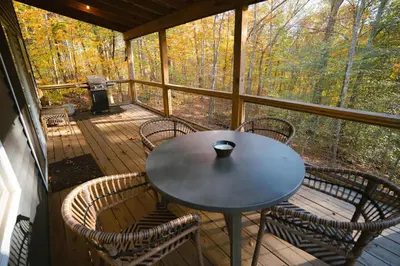a table and chairs on a screened in porch at The Treetop A Hocking Hills Villa Treat in Logan