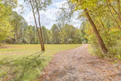 a dirt road in the middle of a field with trees at Romantic Pondside Escape Country Cottage in Paris in Paris