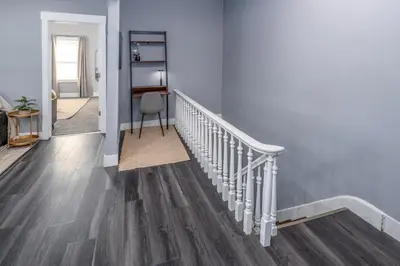 a staircase with white railings and wood floors at Walnut Hills, 5min to UC, Sleeps 7ppl, Lux Beds, Smart TVs in Cincinnati
