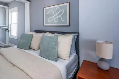 a bedroom with a bed with pillows and a lamp at Walnut Hills, 5min to UC, Sleeps 7ppl, Lux Beds, Smart TVs in Cincinnati