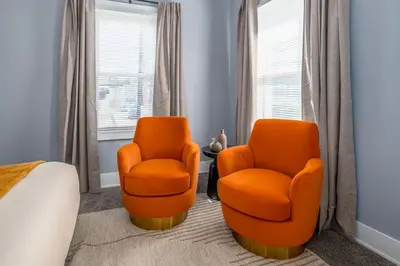 two orange chairs in a room with a bed at Walnut Hills, 5min to UC, Sleeps 7ppl, Lux Beds, Smart TVs in Cincinnati