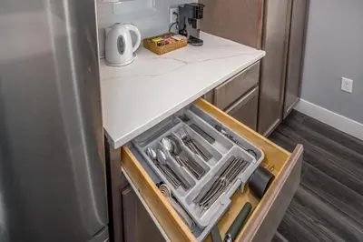 an open drawer in a kitchen with a refrigerator at Walnut Hills, 5min to UC, Sleeps 7ppl, Lux Beds, Smart TVs in Cincinnati