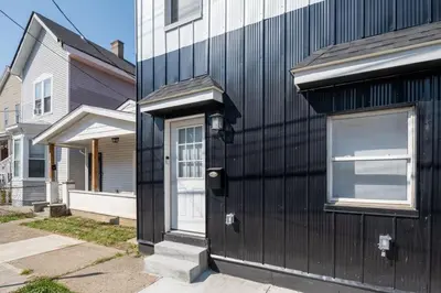 a black building with a door next to a house at Walnut Hills, 5min to UC, Sleeps 7ppl, Lux Beds, Smart TVs in Cincinnati