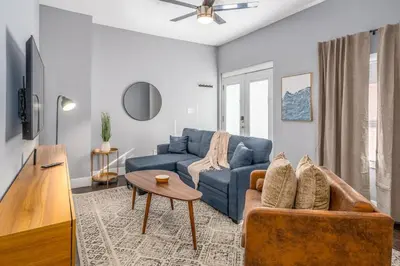 a living room with a blue couch and a table at Prime Walnut Hills, 5min to UC, Lux King Beds, Sleep 6ppl, Smart TVs in Cincinnati