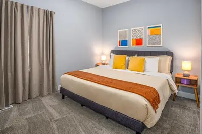 a bedroom with a large bed with yellow pillows at Prime Walnut Hills, 5min to UC, Lux King Beds, Sleep 6ppl, Smart TVs in Cincinnati