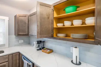 a kitchen with wooden cabinets and white counter tops at Prime Walnut Hills, 5min to UC, Lux King Beds, Sleep 6ppl, Smart TVs in Cincinnati