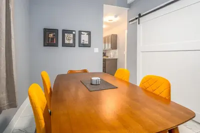 a dining room with a wooden table and yellow chairs at Prime Walnut Hills, 5min to UC, Lux King Beds, Sleep 6ppl, Smart TVs in Cincinnati