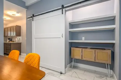 a sliding barn door in a kitchen with a table and chairs at Prime Walnut Hills, 5min to UC, Lux King Beds, Sleep 6ppl, Smart TVs in Cincinnati