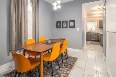 a dining room with a wooden table and yellow chairs at Prime Walnut Hills, 5min to UC, Lux King Beds, Sleep 6ppl, Smart TVs in Cincinnati
