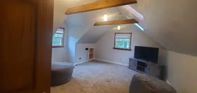 an attic room with a tv and a living room at Cottage in the Woods in Washington