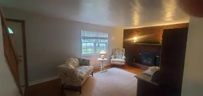 a living room with two chairs and a fireplace at Cottage in the Woods in Washington