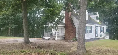 a white house with a brick chimney and two trees at Cottage in the Woods in Washington