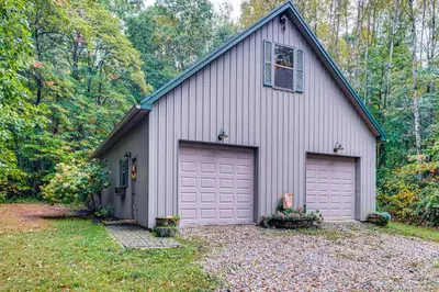 a house with two garage doors in a yard at Hot Tub Haven 10 Mi to Hocking Hills State Park! in Amanda