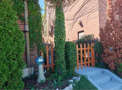 a fence in front of a house with a tree at The Boulevard Stay in Cleveland