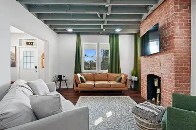 a living room with a couch and a brick wall at Cozy escape with Hot Tub, ideal for family & friends in Columbus