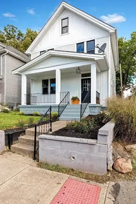 a white house with a porch and stairs in front at Cozy escape with Hot Tub, ideal for family & friends in Columbus