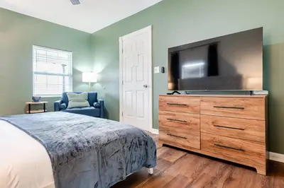 a bedroom with a bed and a flat screen tv at 5BR/3BA*Game Room*FirePit*Theater*3 mins to ARK! in Williamstown