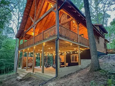 a large wooden house with a wrap around porch at Cheerful Cabin Nestled in Serene Wooded Ravine in Logan