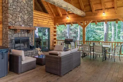 a living room with a stone fireplace in a log cabin at Cheerful Cabin Nestled in Serene Wooded Ravine in Logan