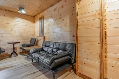 a leather couch in a room with wooden walls at Cheerful Cabin Nestled in Serene Wooded Ravine in Logan